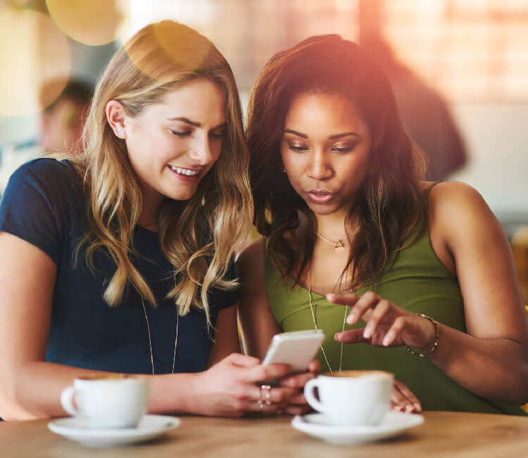 A woman showing her friend what's on her phone screen