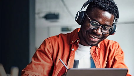 man working on his laptop while wearing headphones