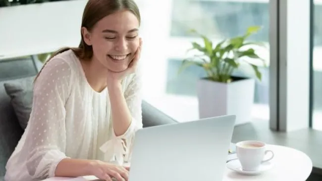 A smiling woman looking at her laptop
