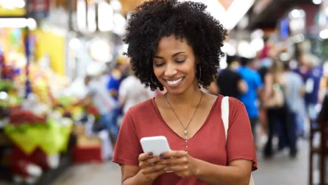 A smiling woman looking at her phone