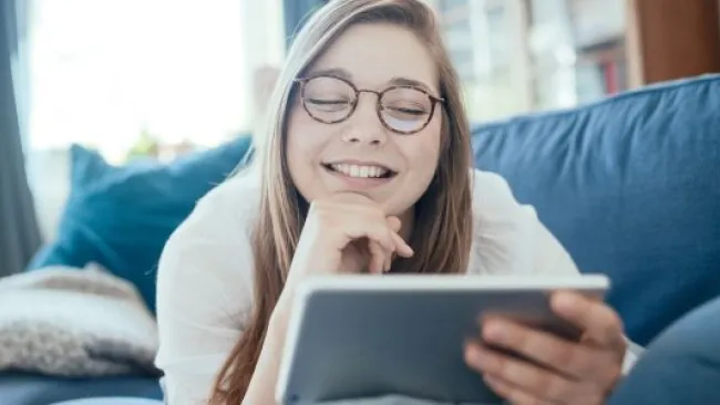 A woman on the couch looking at her tablet