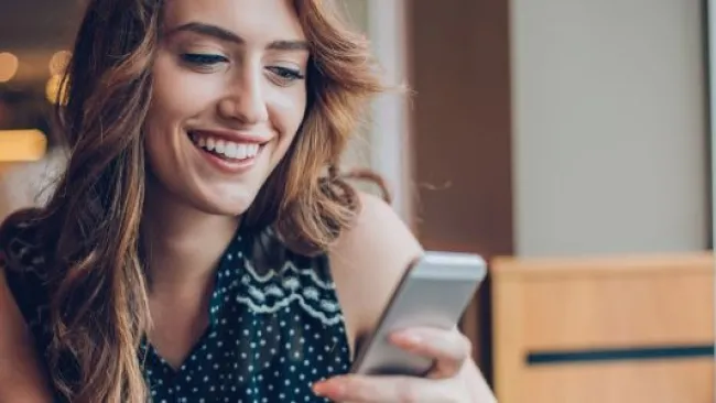A woman smiling while checking her phone