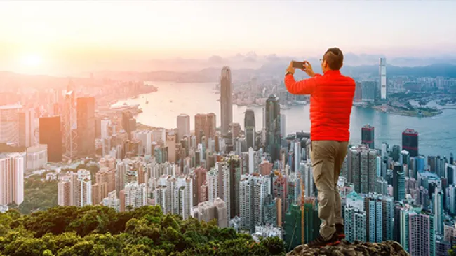A man taking a photo of the city view from a mountain