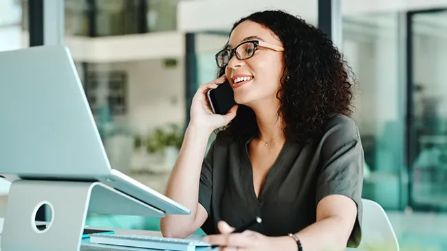 Woman working on laptop and talking on phone