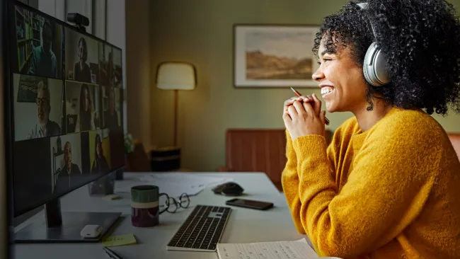 Woman smiling while looking into camera during online meeting