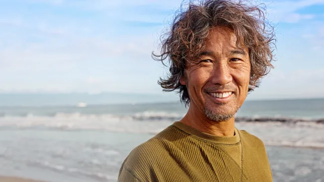 Man walking along a beach smiling at the camera