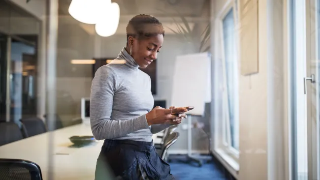 Smiling woman looking at her smartphone in an office