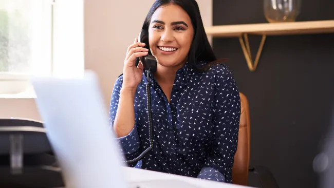 Woman smiling and holding phone at desk