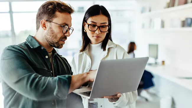 Man and woman in an office looking at a laptop