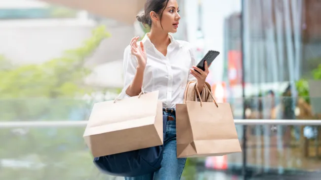 Woman on her phone and carrying shopping bags