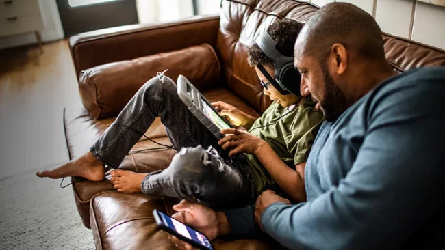 Father watching his child play a mobile game