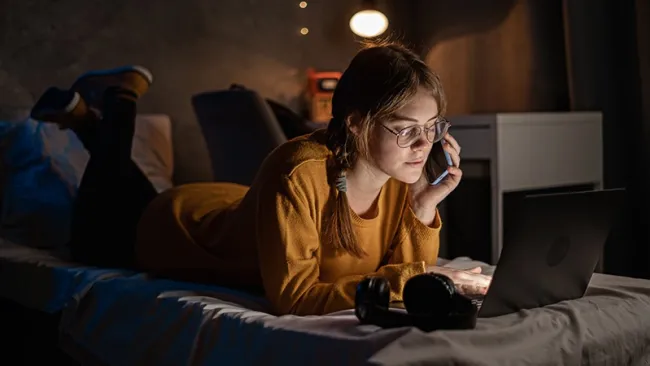 Woman using her laptop while laying in bed