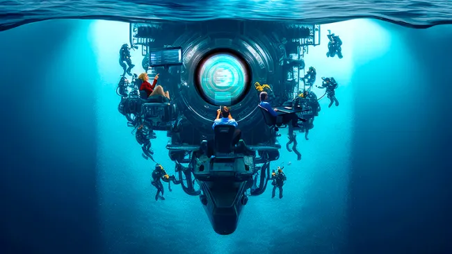 People working alongside a submarine underwater, at desks