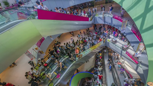 Spiral escalator full of shoppers at a busy mall 