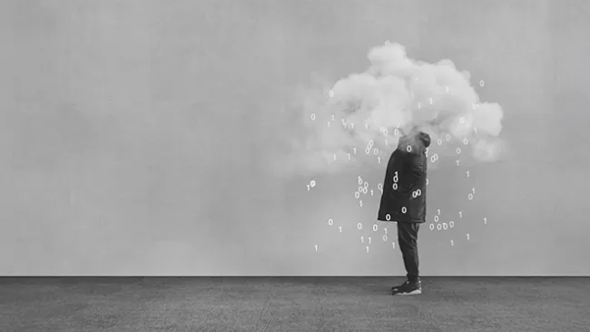 A black and white photo of a person standing, with his or her head obscured by a cloud and the digits 1 and 0 spilling out of the cloud.