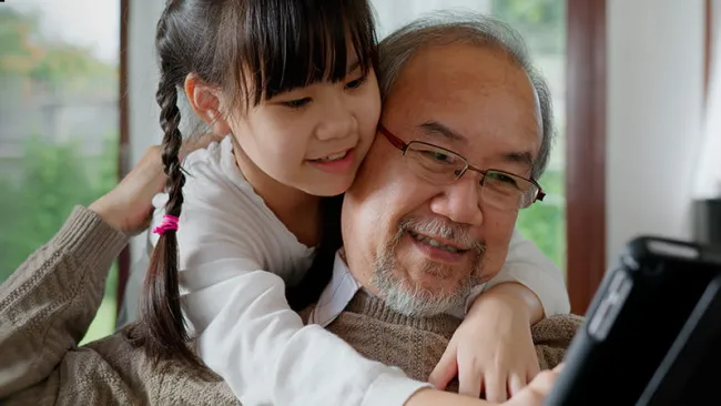 Grandfather looking at a tablet with his grandaughter