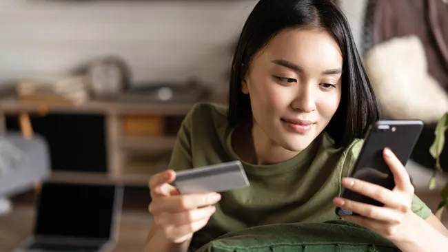 A woman holding a phone on one hand and a card on the other