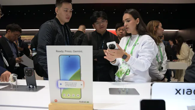 Woman holding a cellphone talking to a man at Mobile World Congress