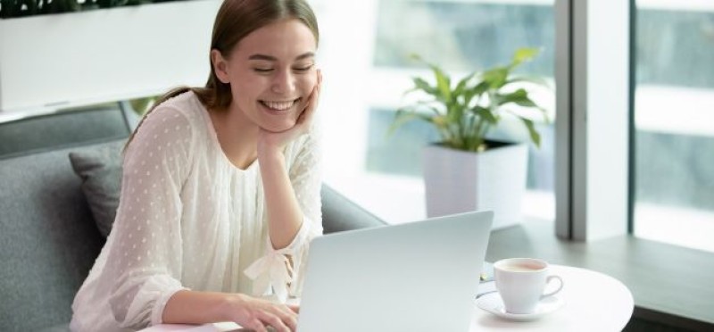 A smiling woman looking at her laptop