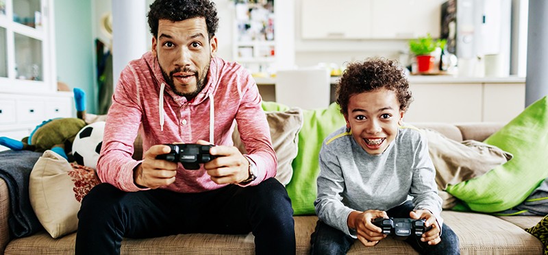 An adult and a child playing PS