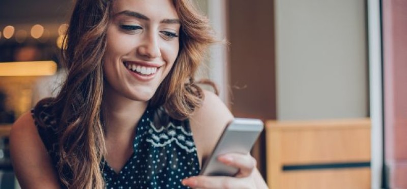 A woman smiling while checking her phone