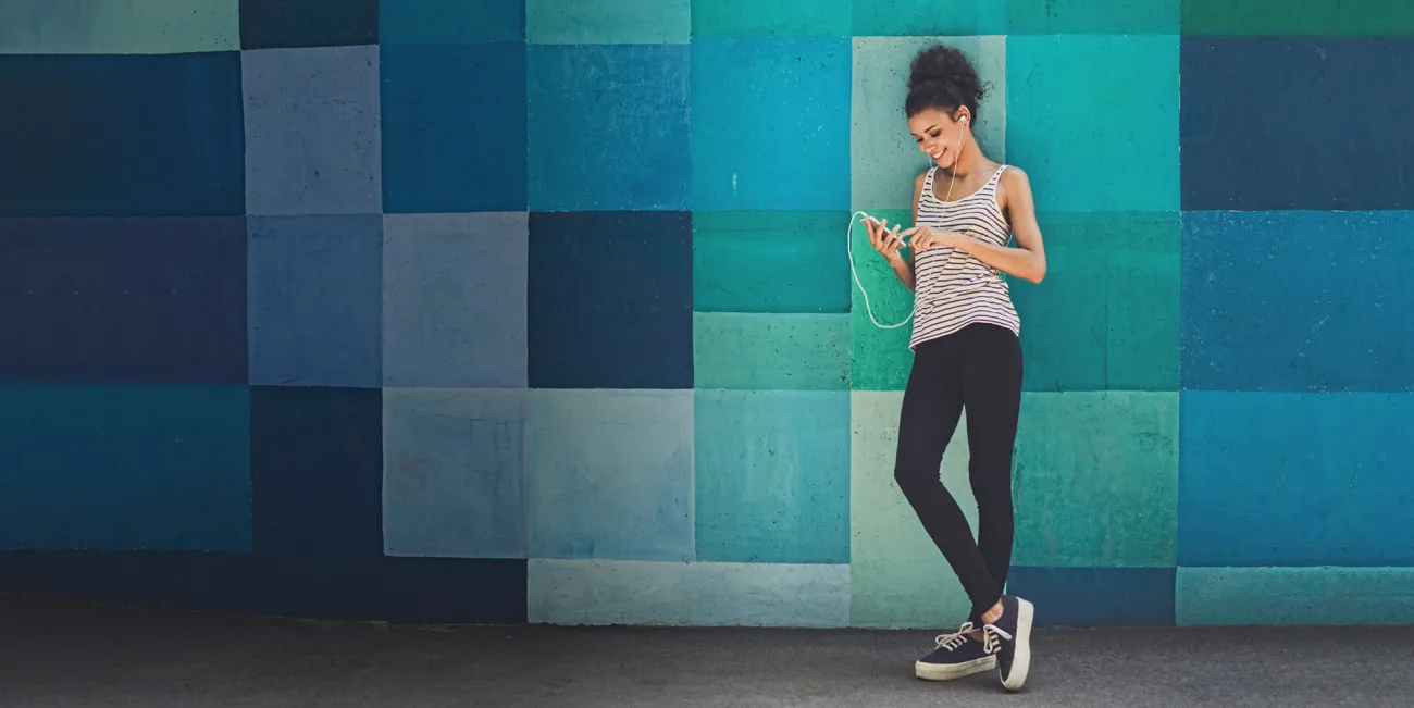 Woman standing against a colorful wall using her phone