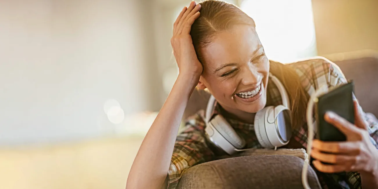 Smiling woman wearing headphones plugged into her phone