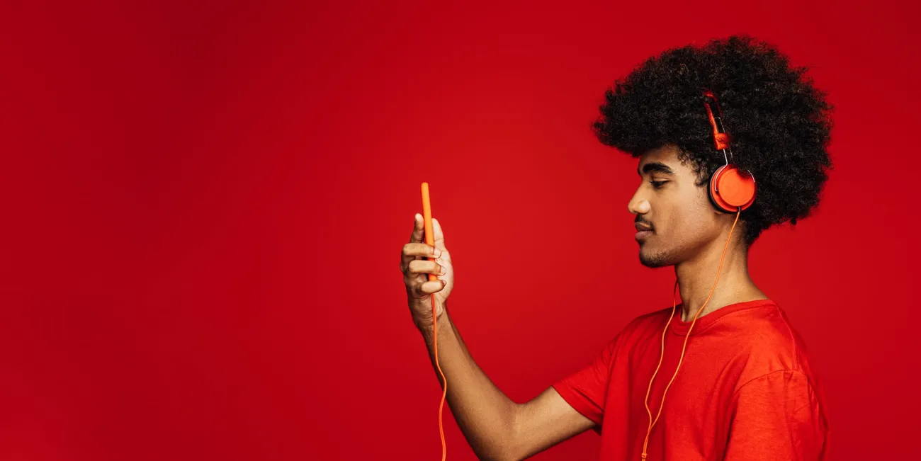 Man wearing headphones and looking left at his phone