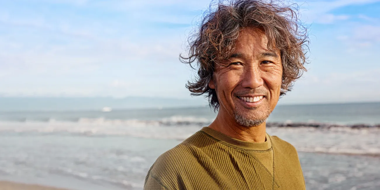 Man walking along a beach smiling at the camera