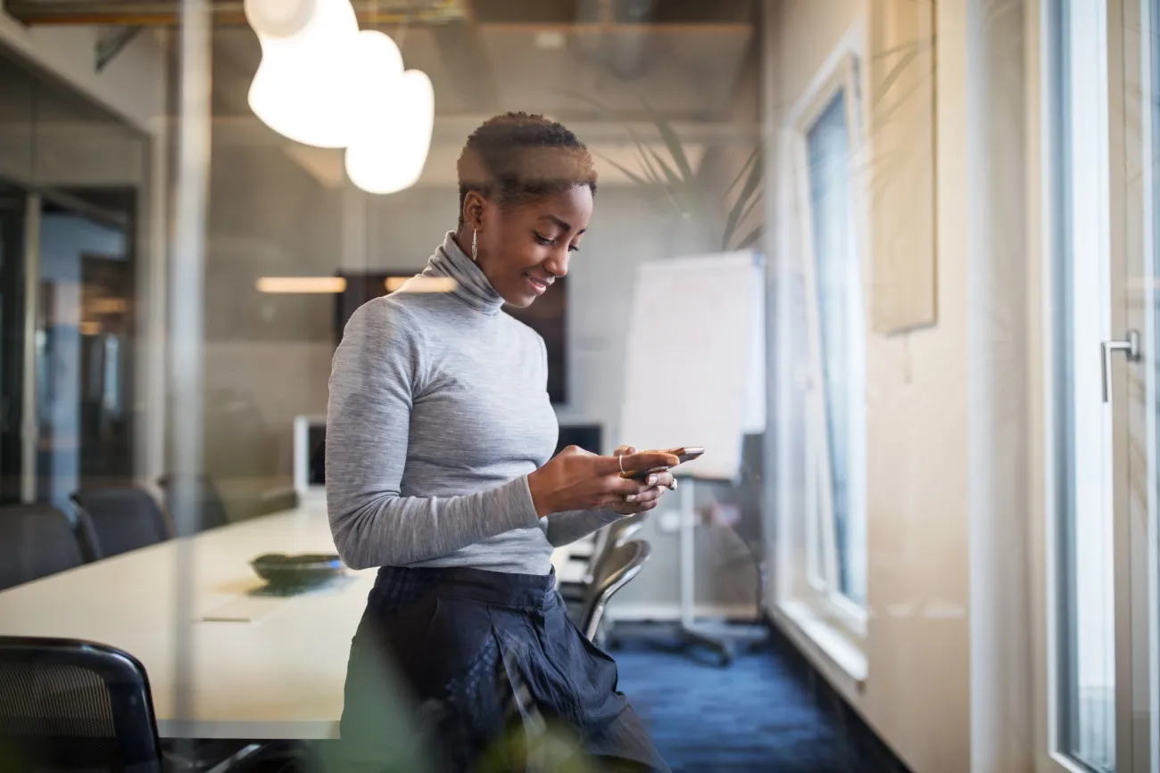 Smiling woman looking at her smartphone in an office