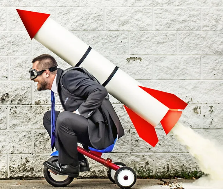 Man riding a tricycle with a rocket on his back