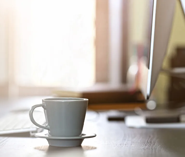 A home office desk with computer and coffee cup on it