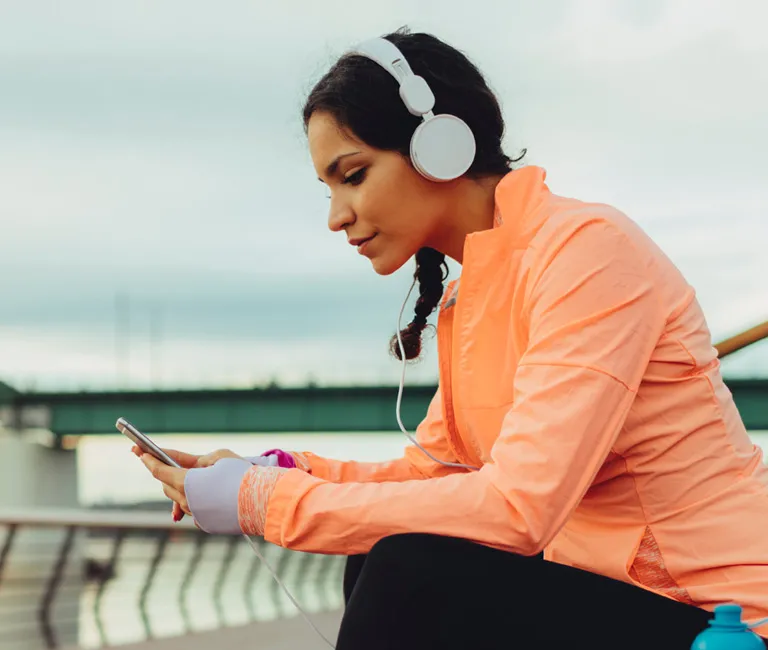 Woman sitting on bench using her phone with earphones