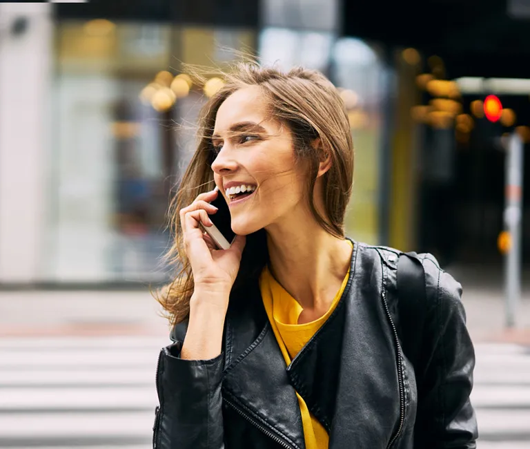 Woman on her phone walking across a sidewalk