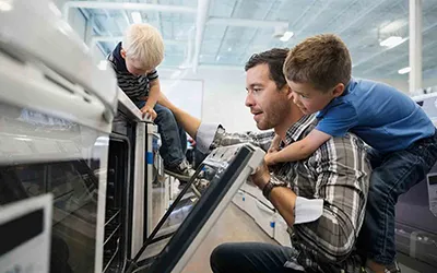 A father and his two young sons shopping for an oven