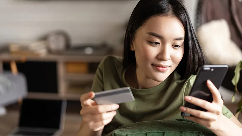 A woman holding a phone on one hand and a card on the other