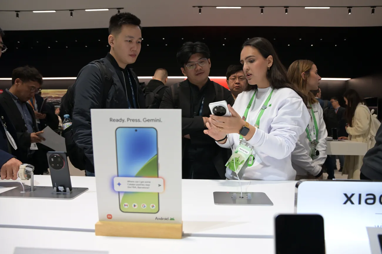 Woman holding a cellphone talking to a man at Mobile World Congress