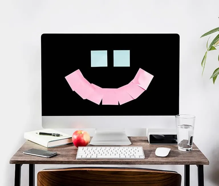Post-it notes on a monitor in the shape of a smiley face