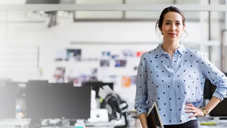 Woman holding a tablet standing in front of an office space