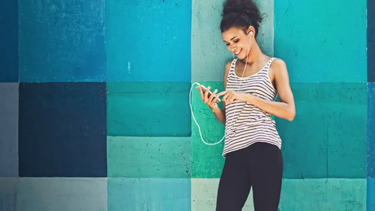 Woman standing against a colorful wall using her phone