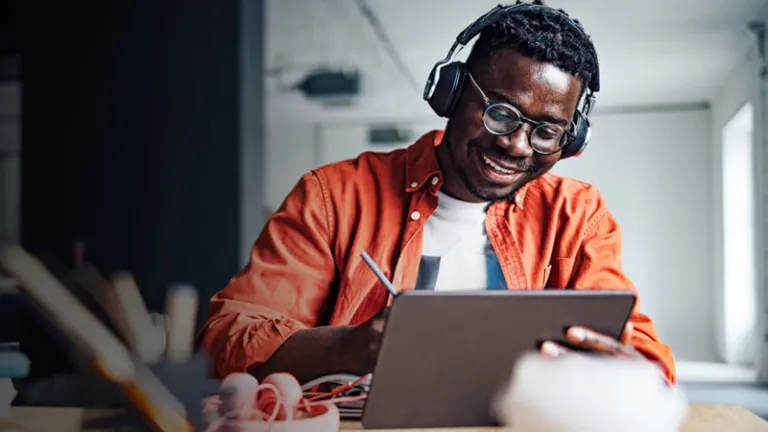 Man working at a desk with a tablet and headphones