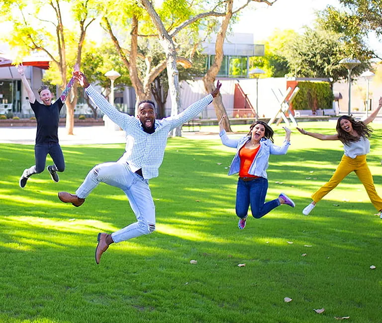 Group of people in a field jumping in celebration