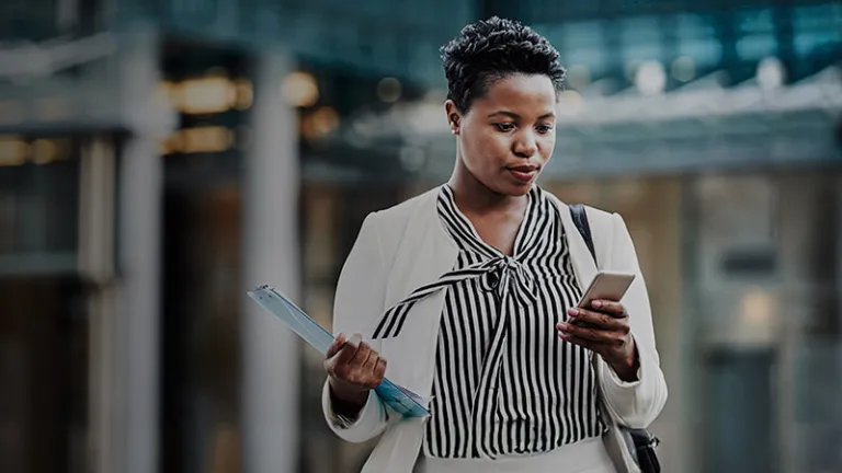 Woman looking at her phone while walking in a city