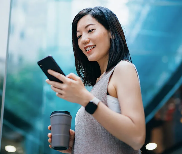 Woman using her phone near a large window